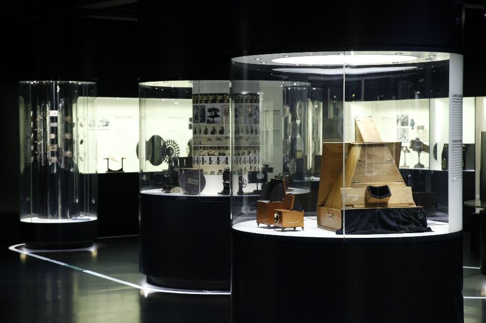 Runde erleuchtete Vitrinen mit Ausstellungsstücken im abgedunkelten Filmmuseum